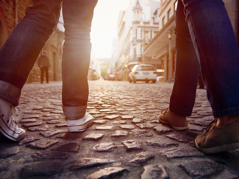 Tourist,couple,walking,on,cobblestone,street,vacation,in,europe,on