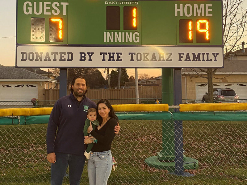 Partner, Paul Tokarz, with his wife and son, Keriann and Isadore, donated a new baseball scoreboard to the Notre Dame College Prep baseball program.
